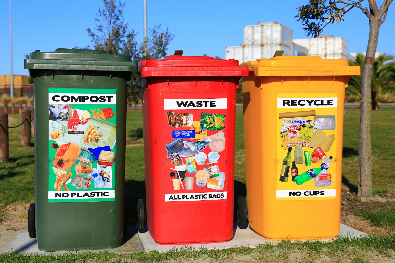 black plastic garbage bin with wheels beside wall